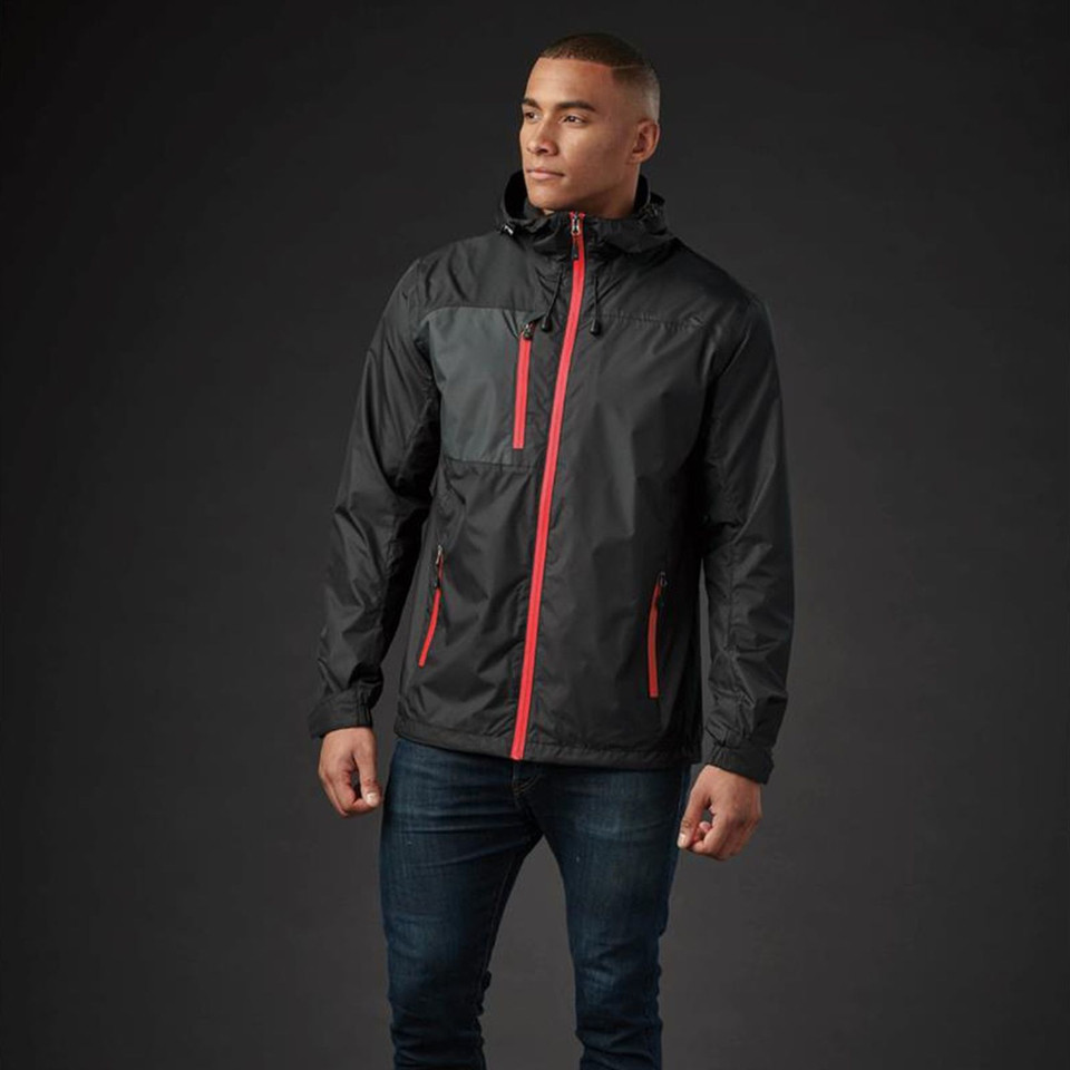 Man wearing black and charcoal waterproof shell jacket with red zip contrast detailing and attached hood