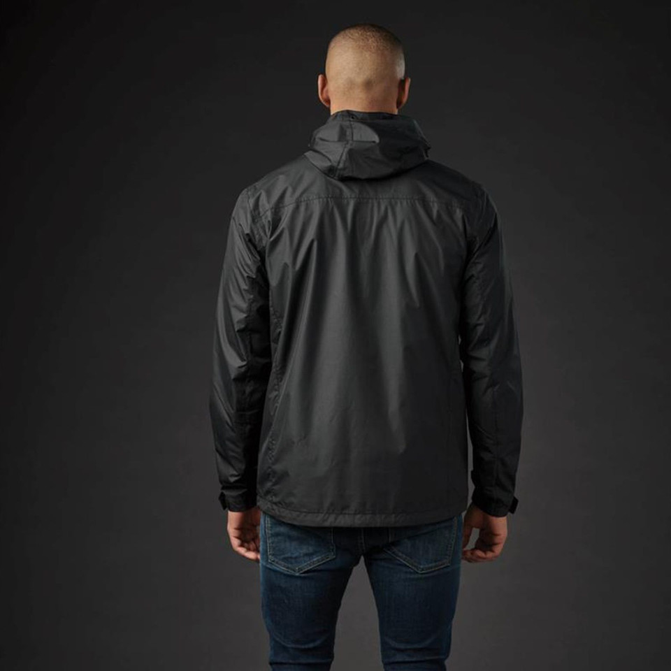Man wearing black waterproof shell jacket from behind, structured hood, lightweight panelled construction, dark studio setting