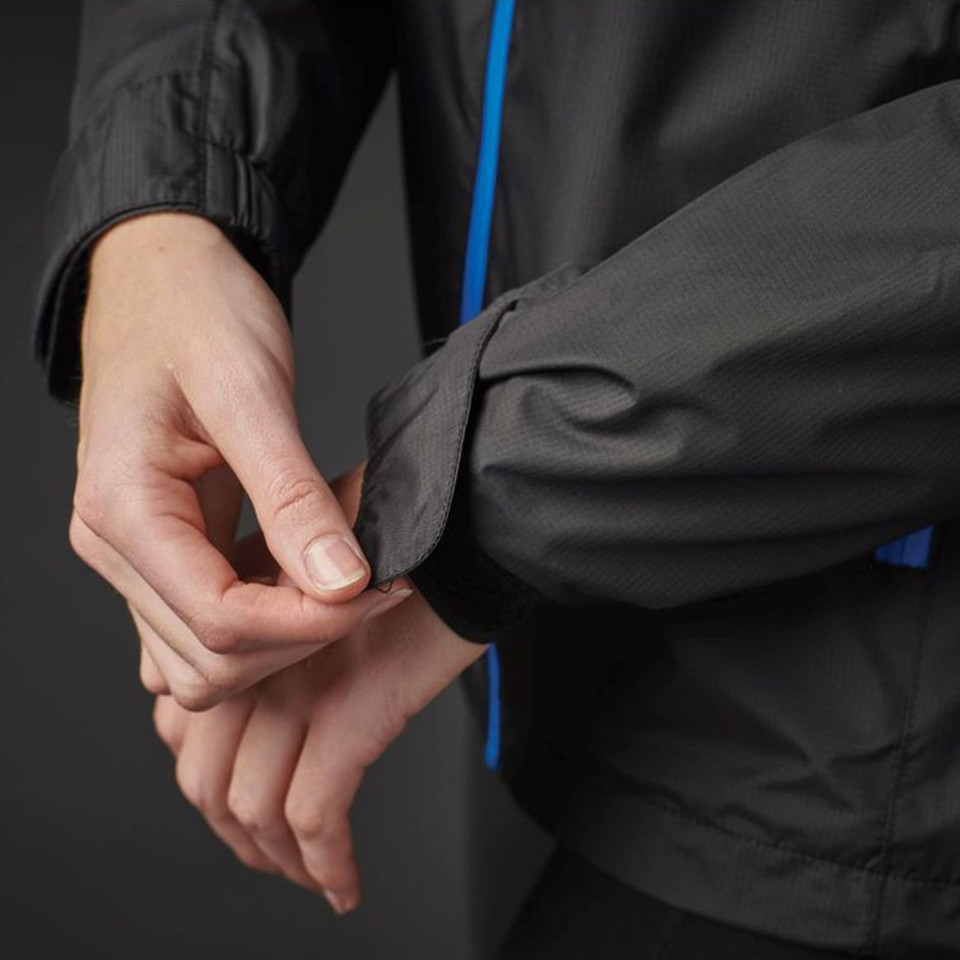 Close-up of charcoal waterproof shell jacket cuff with royal blue contrast piping, adjustable tab detail