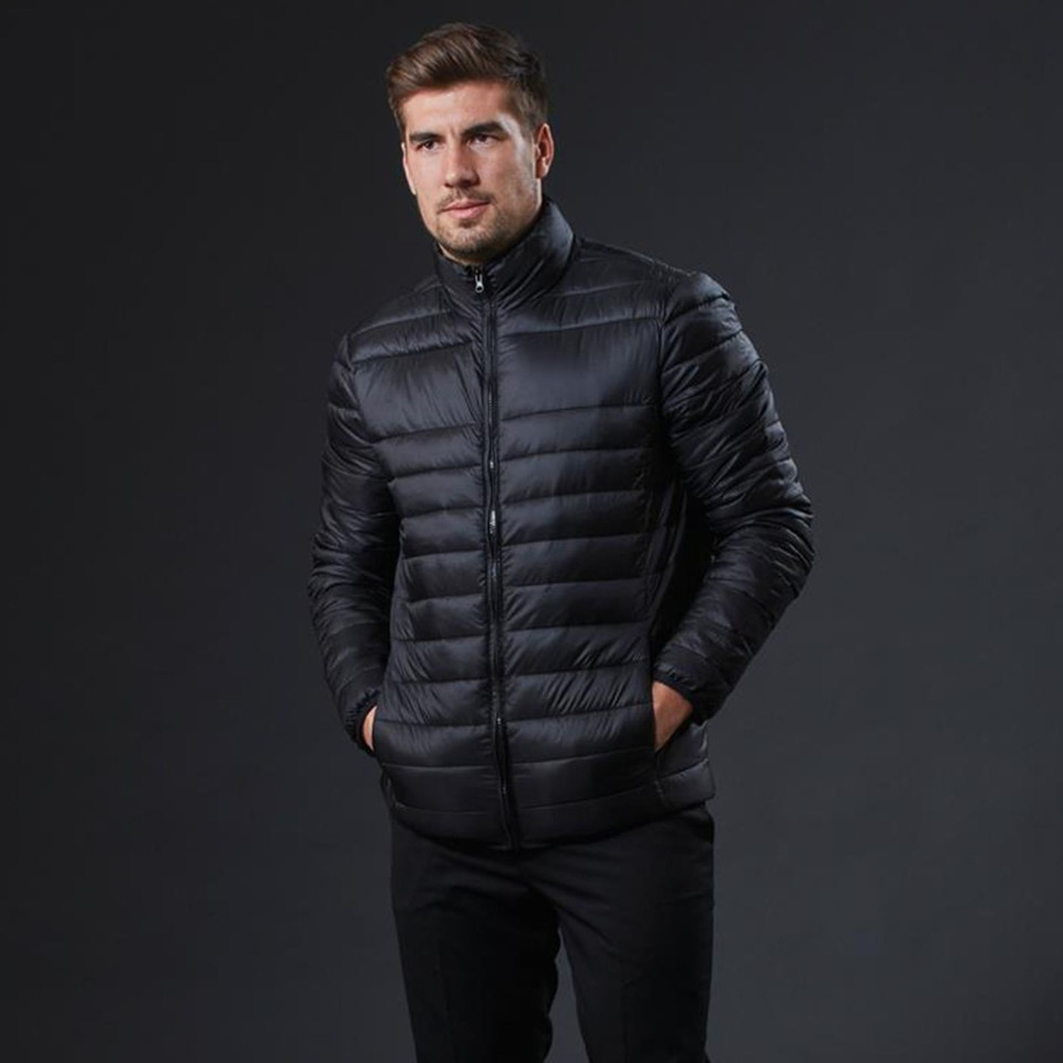 Man wearing a black lightweight puffer jacket with stand collar, zip front, and horizontal quilted channels