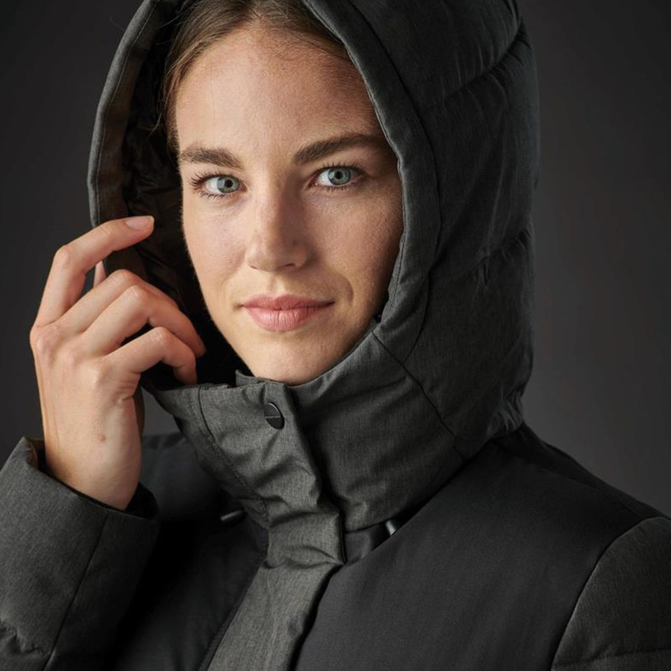 Woman wearing a charcoal insulated parka with structured quilted hood framing the face