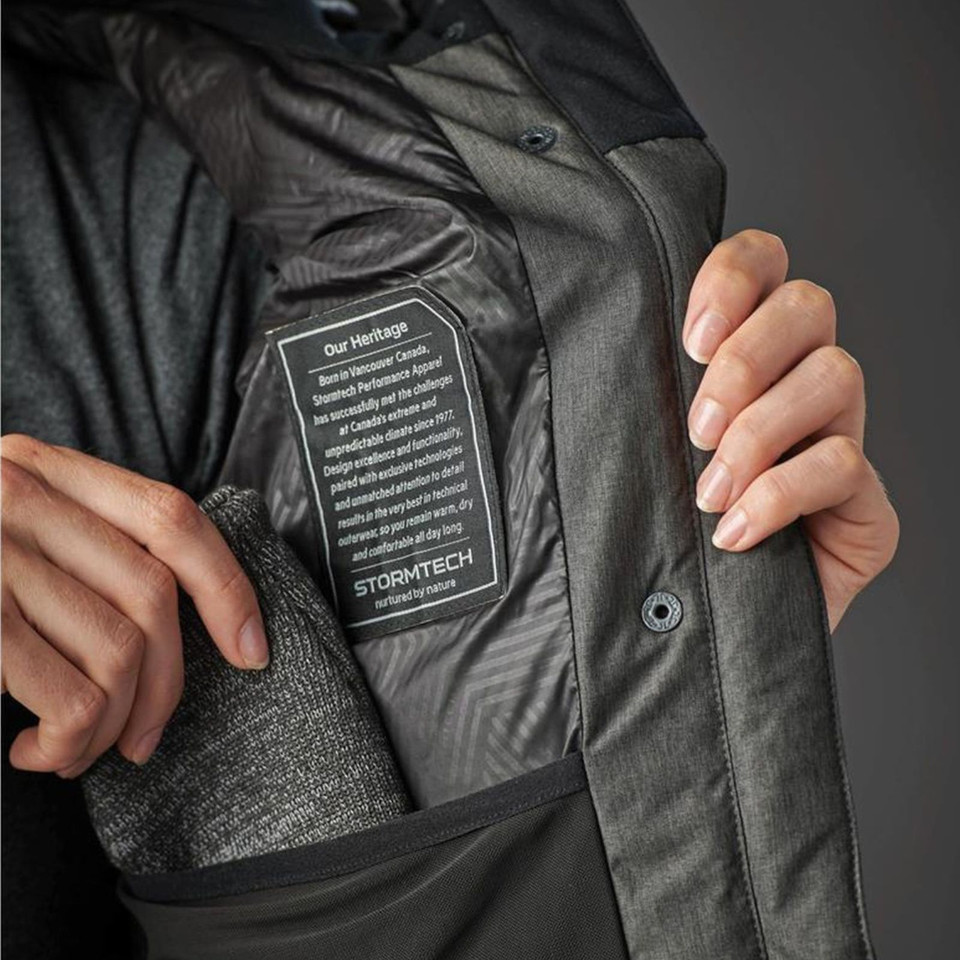 Interior lining detail of charcoal insulated women's parka showing quilted panelling, inner pocket and Stormtech heritage label