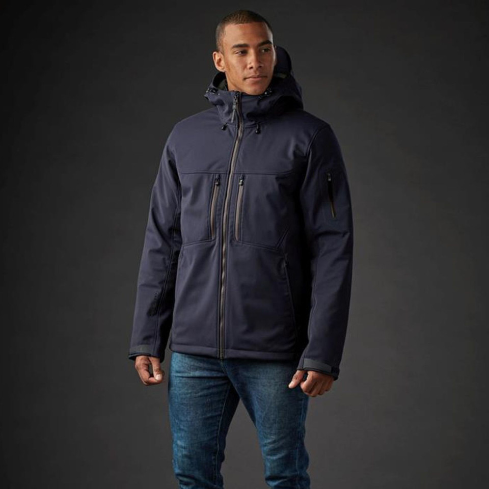 Man wearing navy technical system jacket with adjustable hood, chest zip pockets, and gunmetal zip hardware