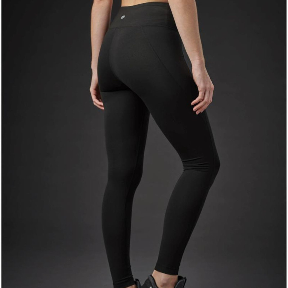 Rear view of model wearing black full-length performance leggings with wide waistband and smooth finish