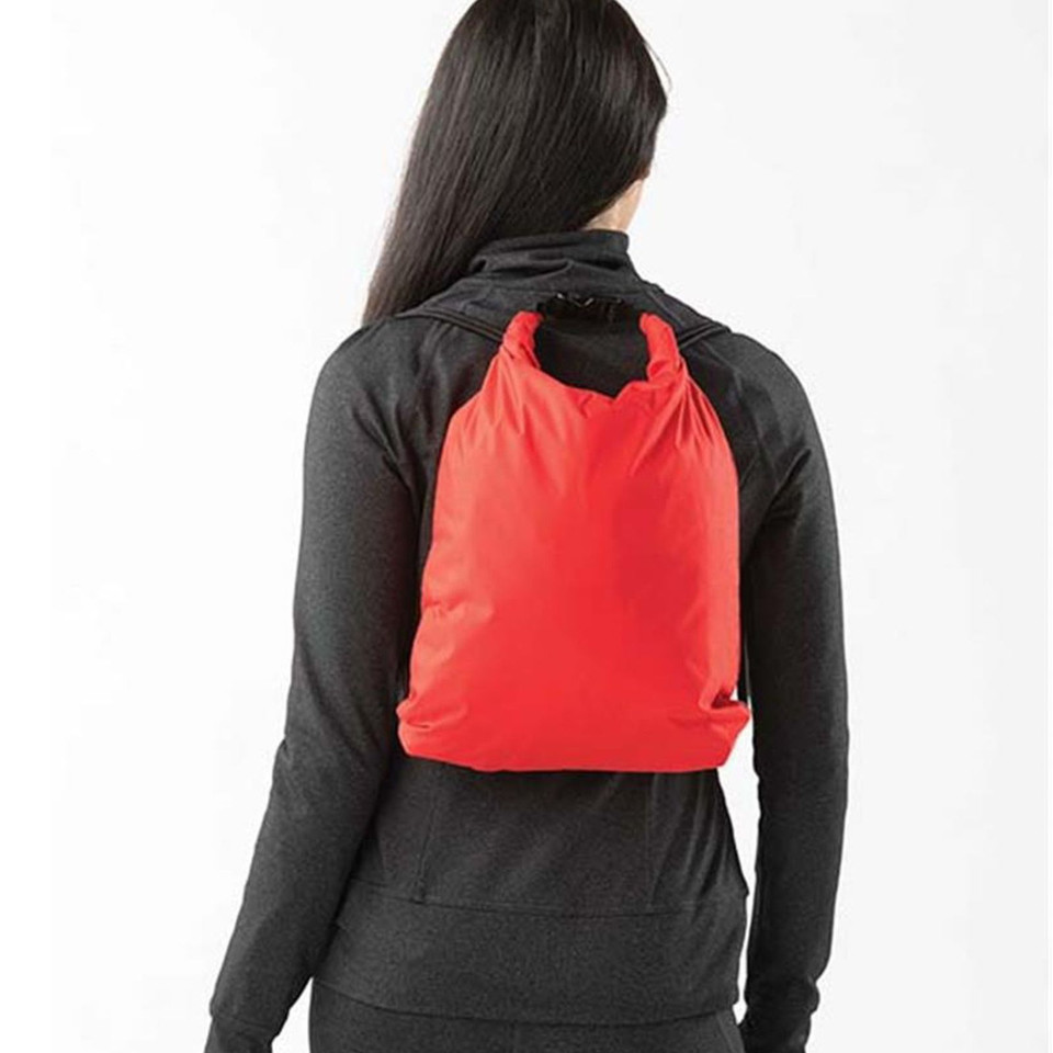 Woman wearing a red roll-top cinch drawstring backpack over a charcoal long-sleeve top, rear view