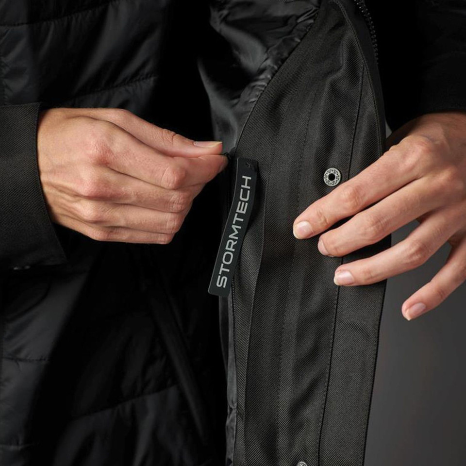 Close-up of black Stormtech jacket zip-off inner layer with branded zip pull and snap button detail