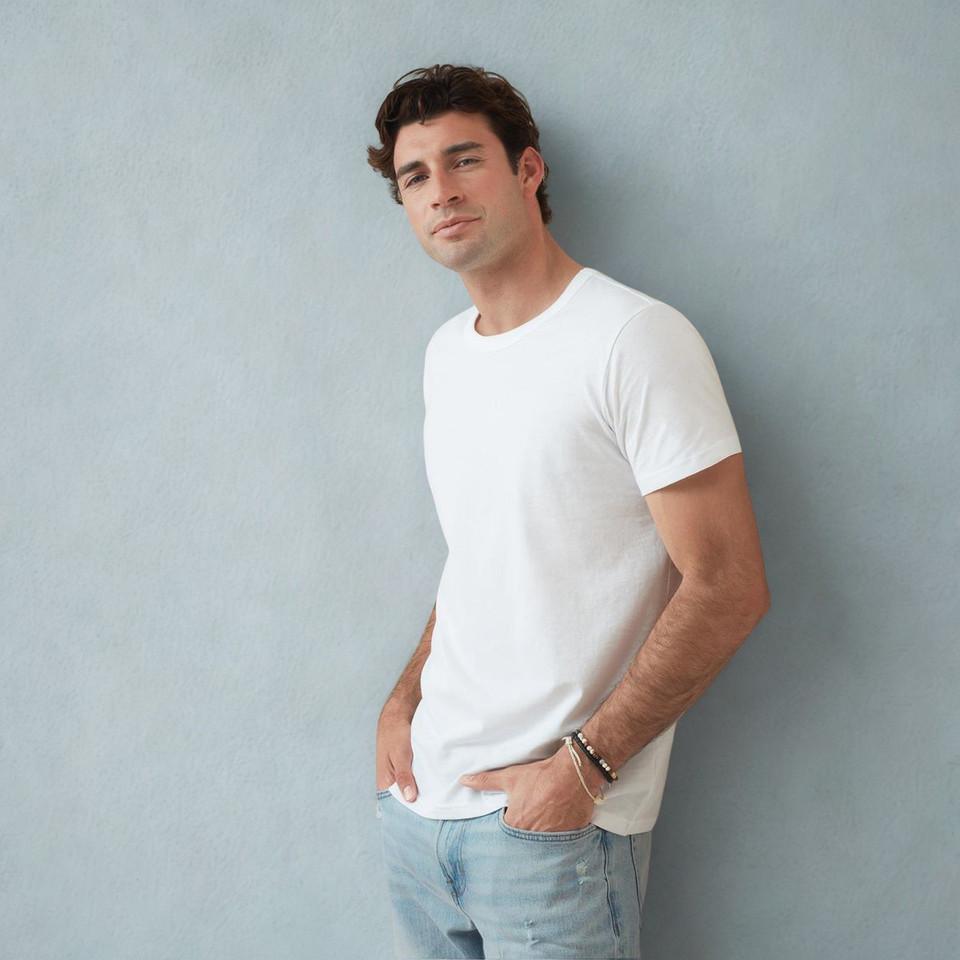 Male model wearing a white slim-fit crew neck cotton T-shirt with short sleeves against a grey wall