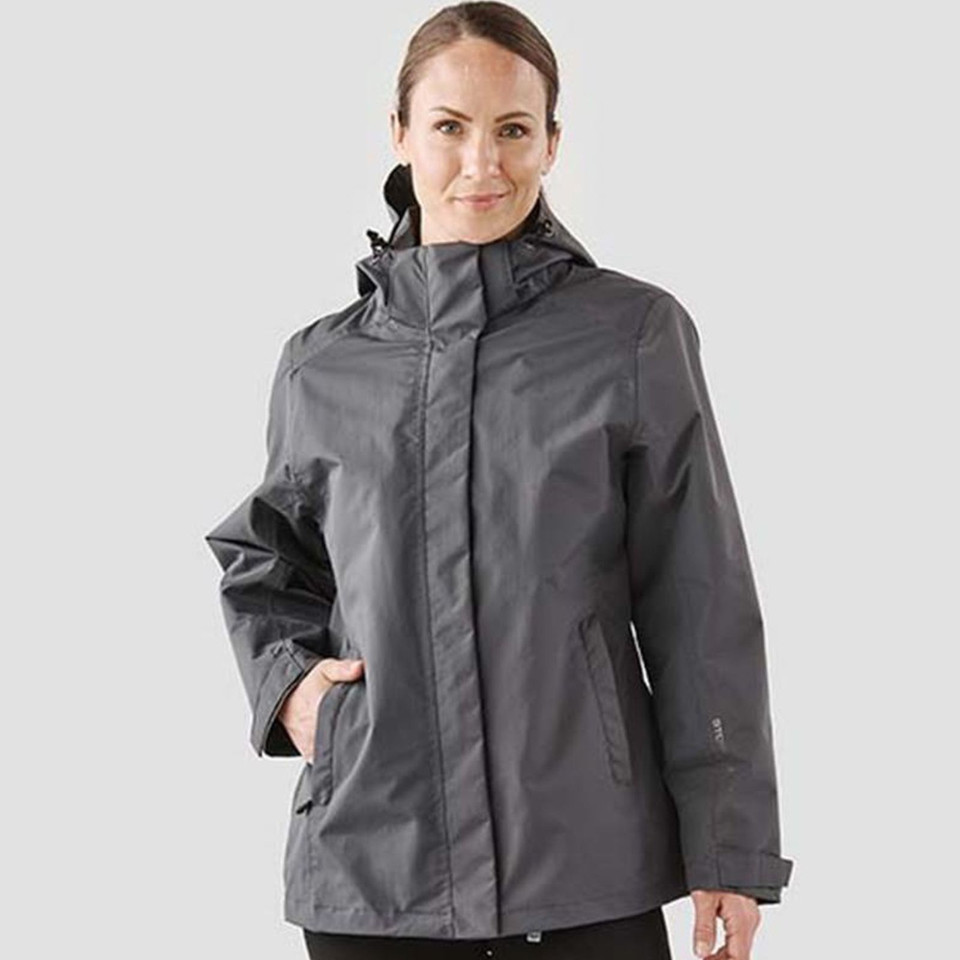 Woman wearing charcoal grey Stormtech waterproof system jacket with zip-off hood and zip pockets
