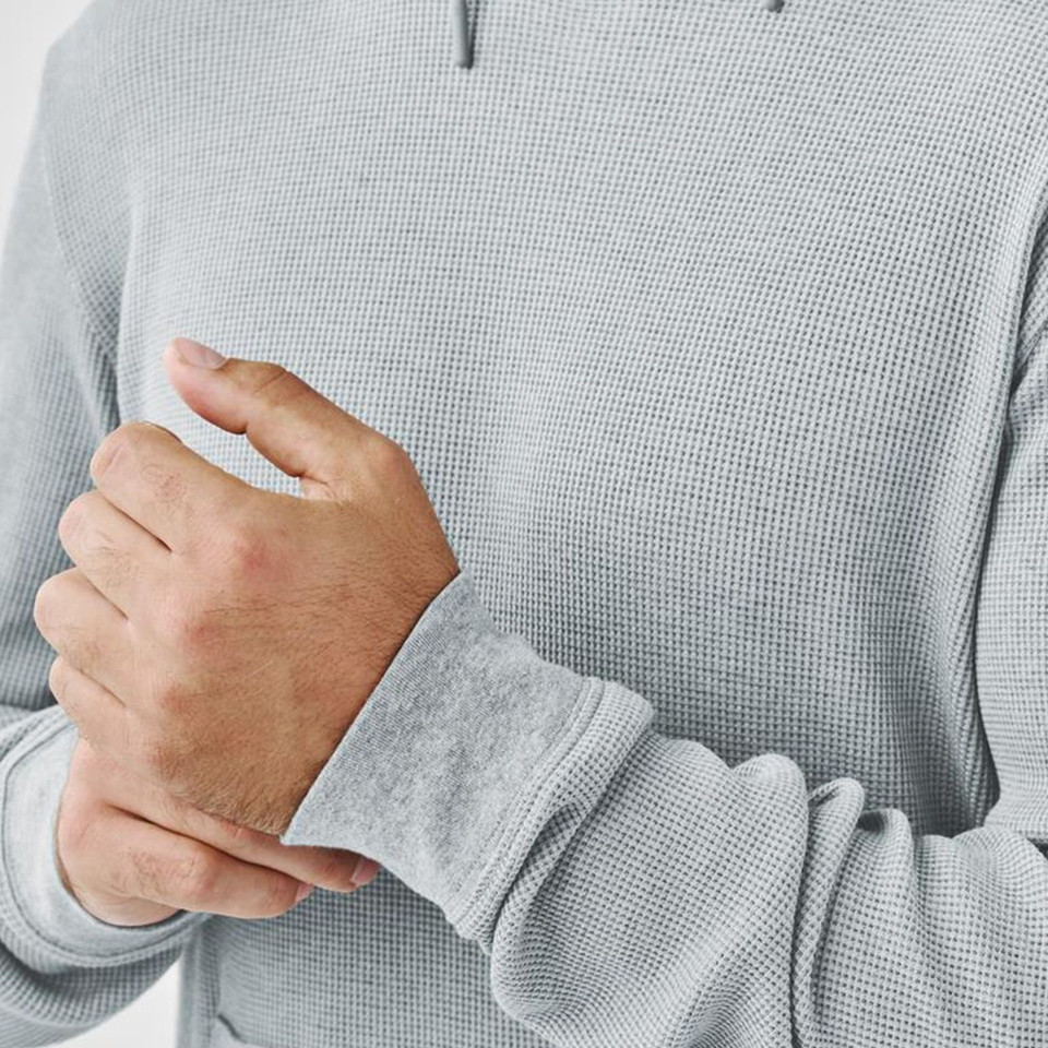Close-up of light grey waffle-knit hoody on male model showing textured fabric and ribbed cuff detail