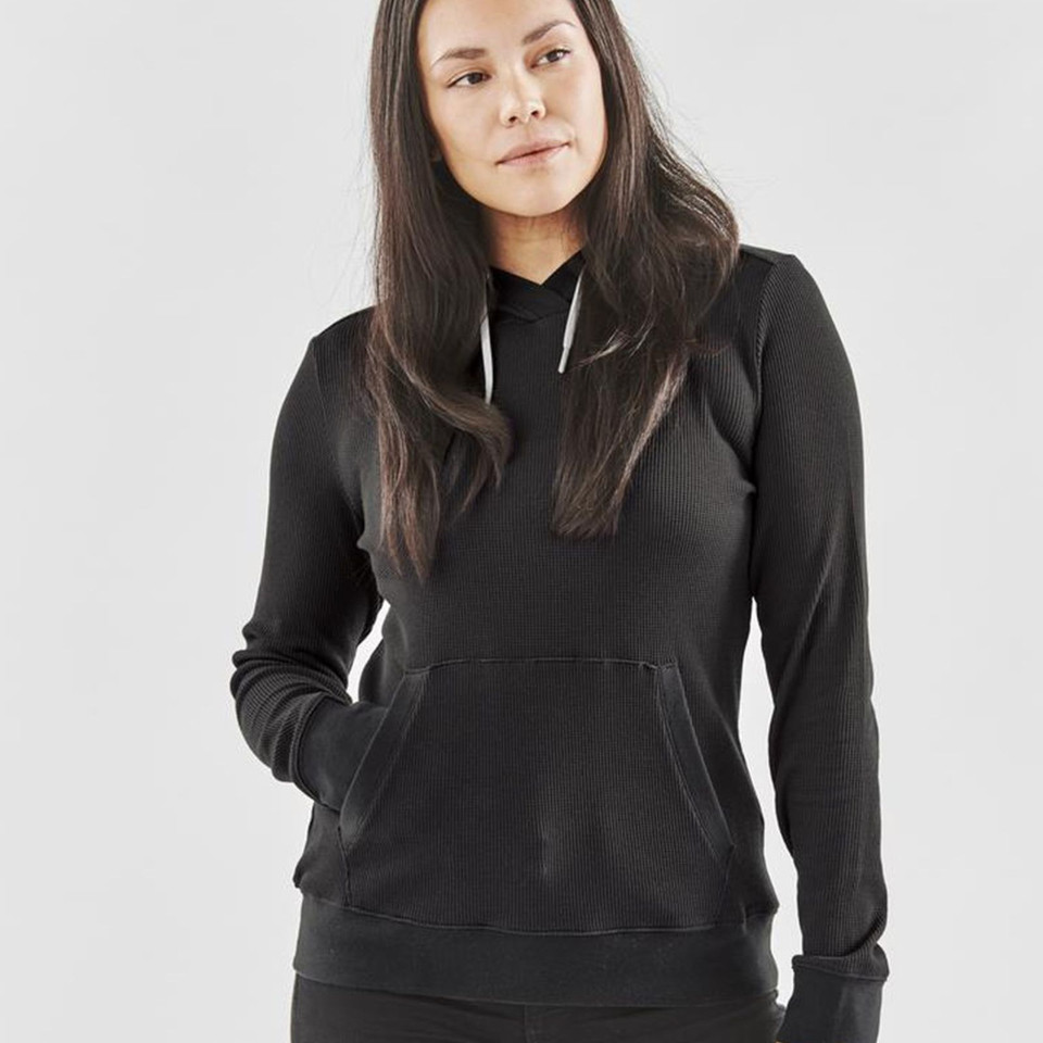 Woman wearing a black waffle-knit pullover hoodie with kangaroo pocket and drawstring hood