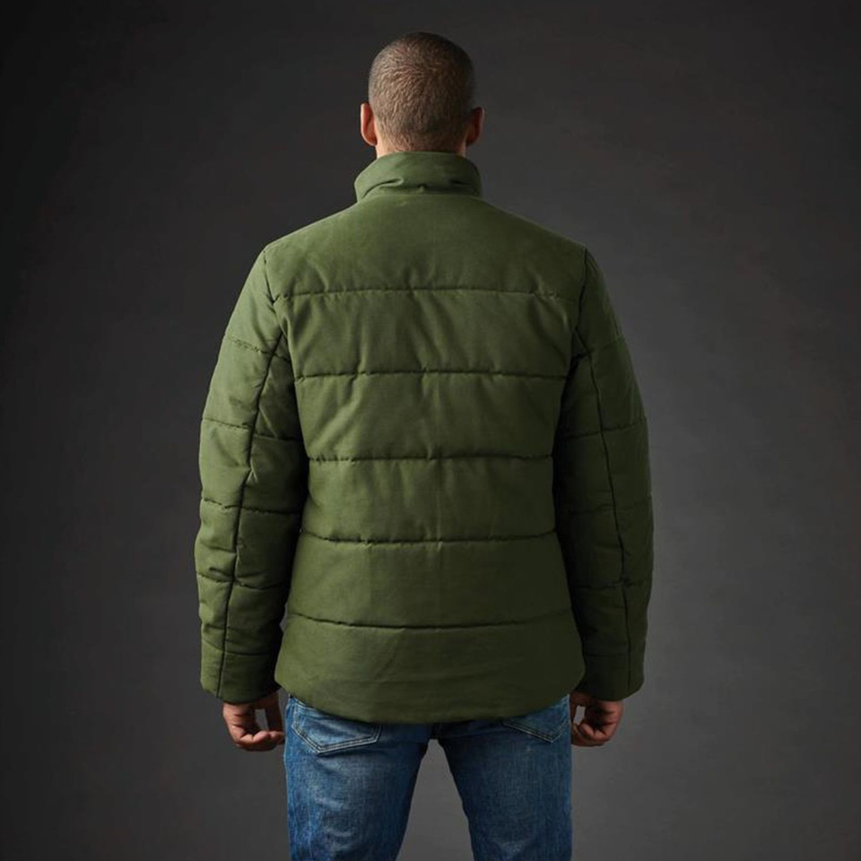 Rear view of man wearing olive green quilted canvas thermal jacket with horizontal baffle panels and stand collar
