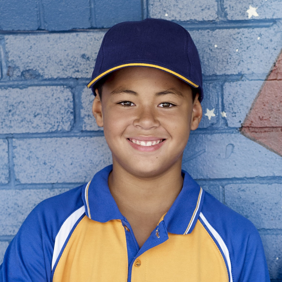 Child wearing navy baseball cap with gold sandwich peak brim, smooth front panel, structured crown