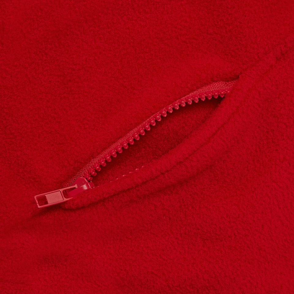 Close-up of red polar fleece fabric with matching red zip pocket detail