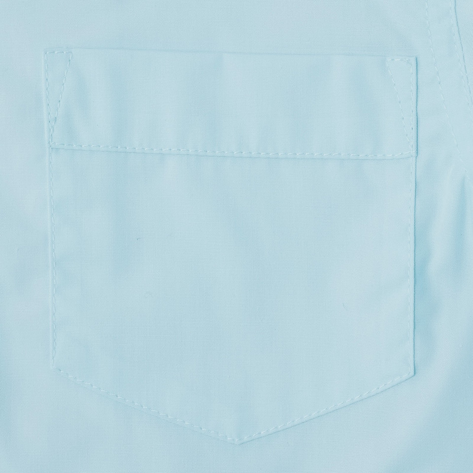 Close-up of sky blue long sleeve blouse showing stitched chest pocket detail on smooth woven fabric