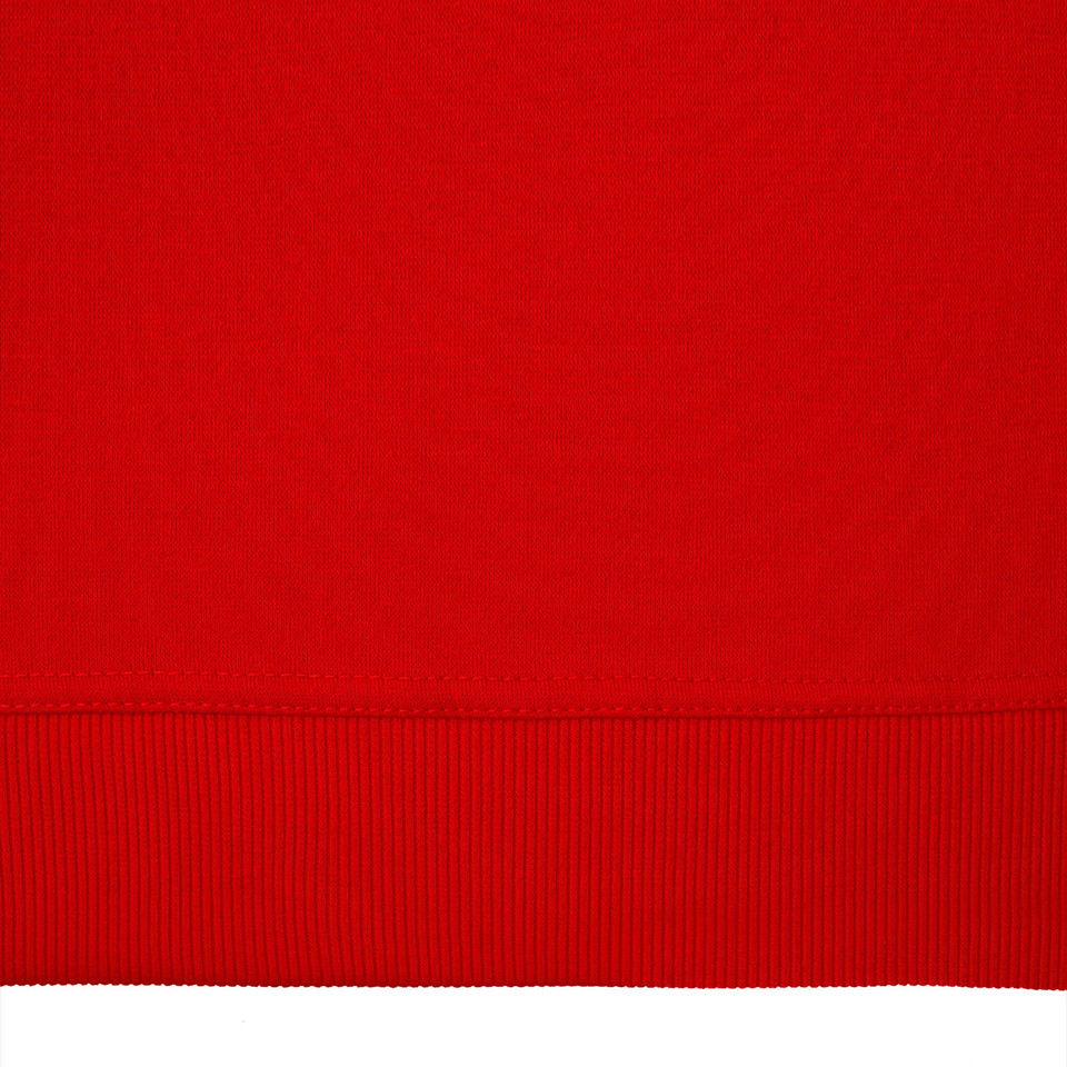 Close-up of red fleece crew neck sweater hem showing ribbed waistband and smooth knit fabric