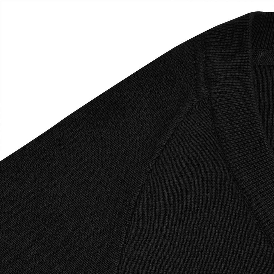 Close-up of black kids knit jumper showing raglan shoulder seam and ribbed crew neckline detail