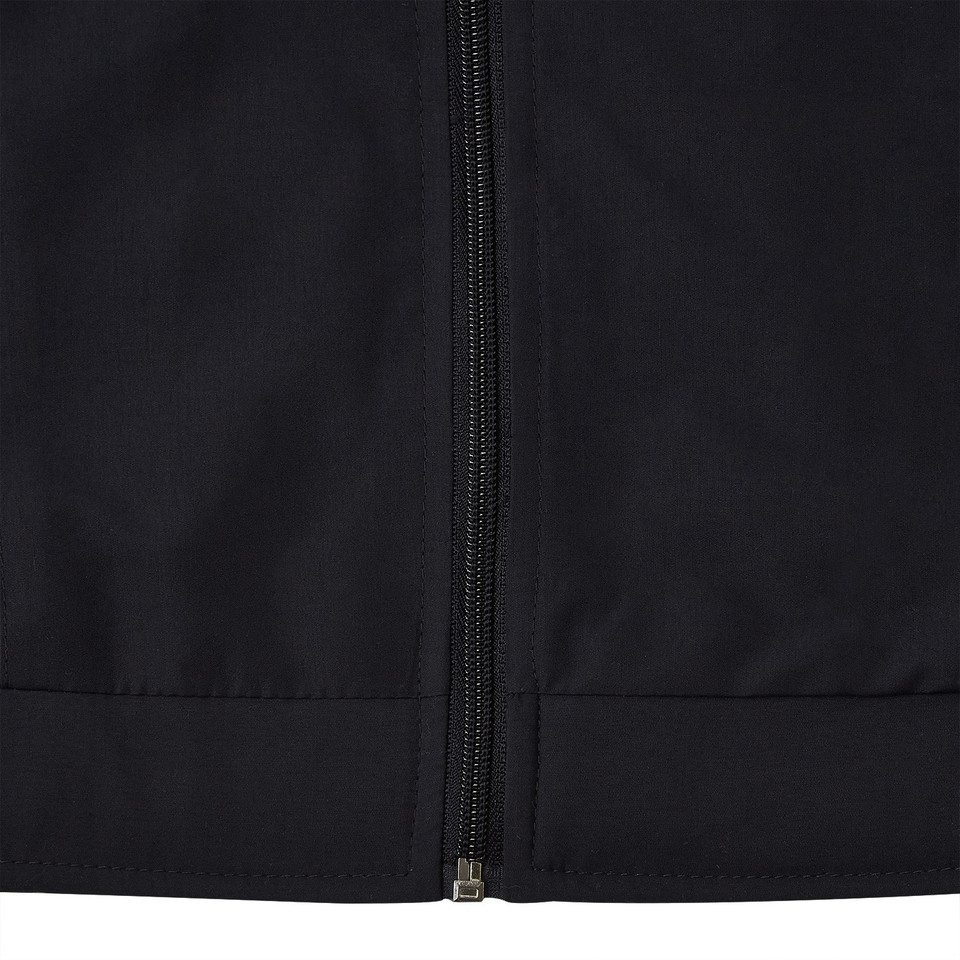 Close-up of black microfibre jacket showing centre-front zip and ribbed hem band