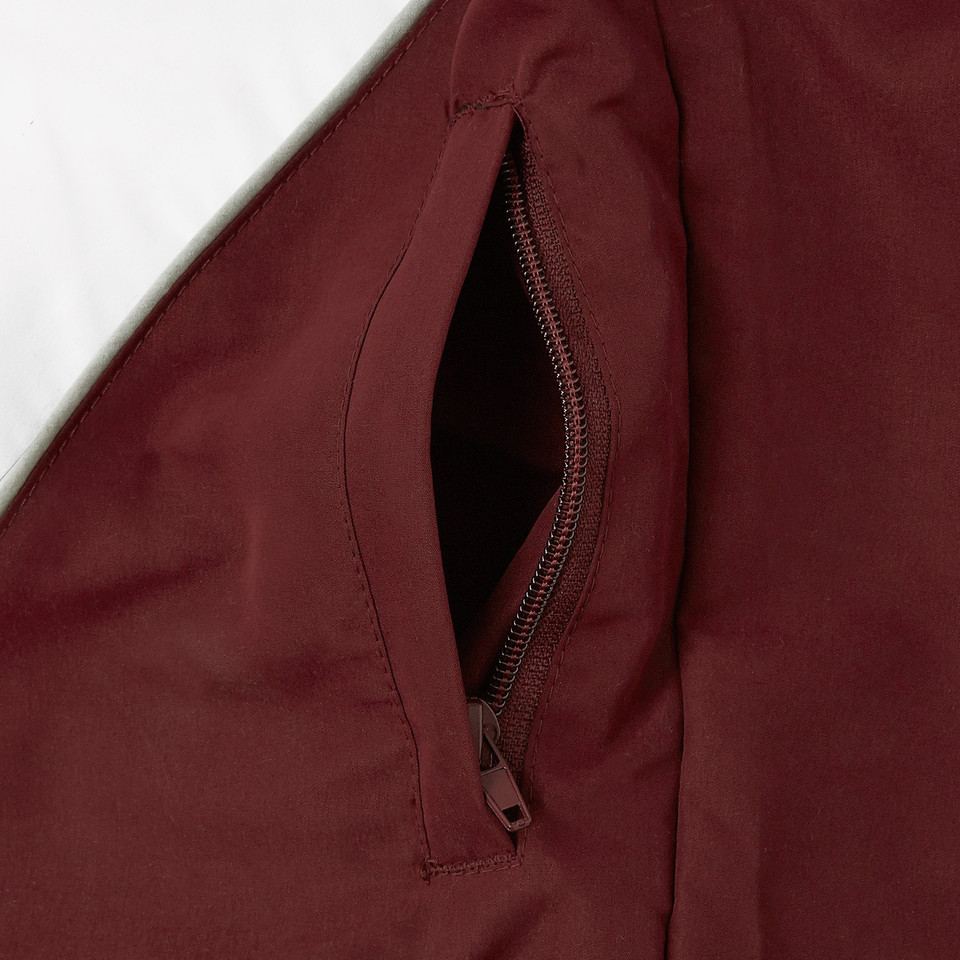 Close-up of open zippered chest pocket on a deep burgundy microfibre sport jacket