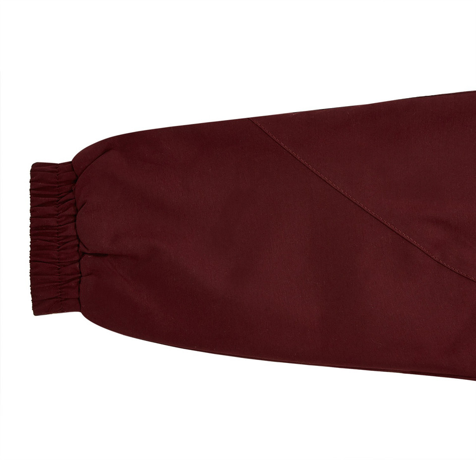 Close-up of maroon microfibre sports jacket sleeve with elasticated cuff and diagonal seam detail