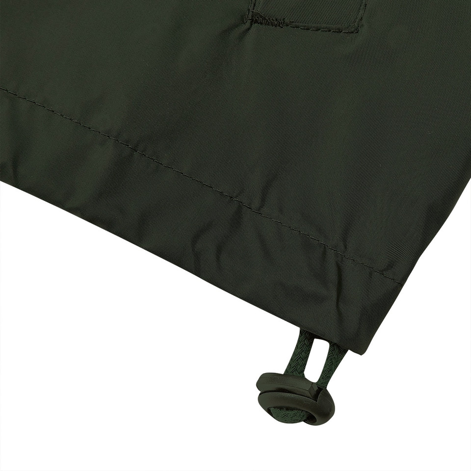 Forest green packable jacket hem detail showing drawcord toggle and chest pocket stitching