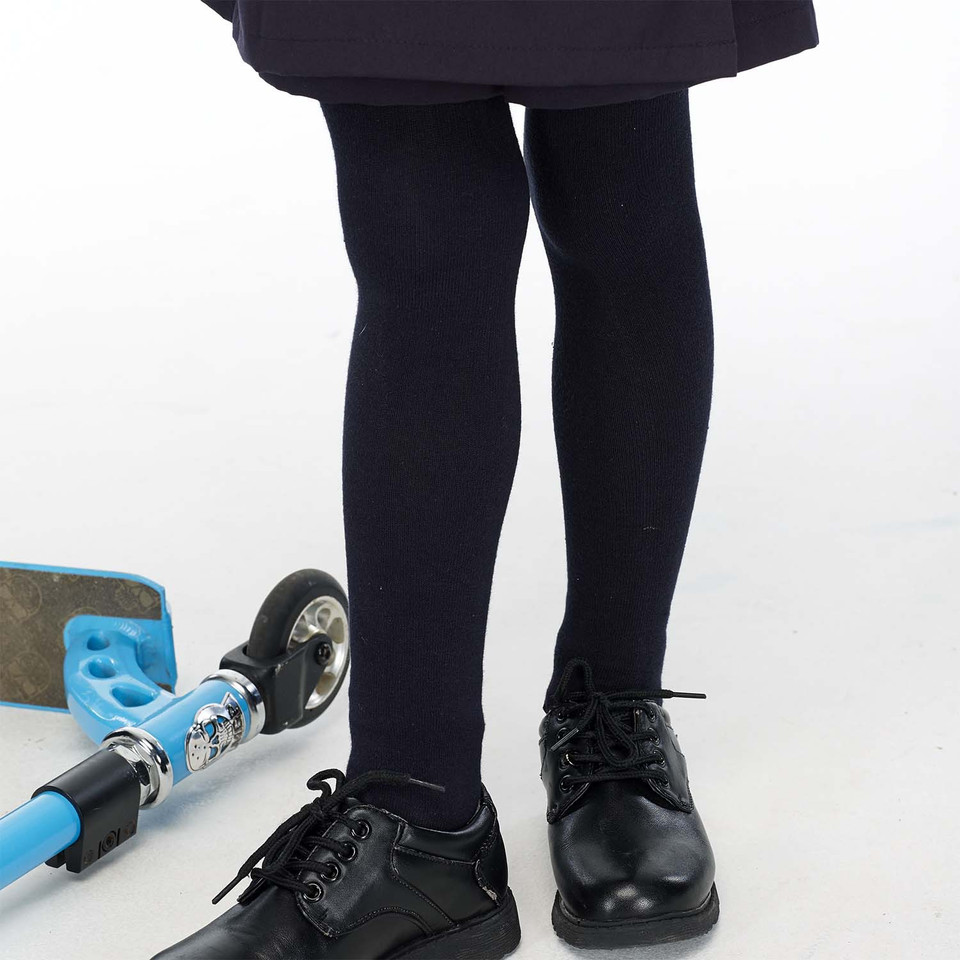 Girl wearing navy blue ribbed school tights with black lace-up shoes and dark skirt, scooter beside her