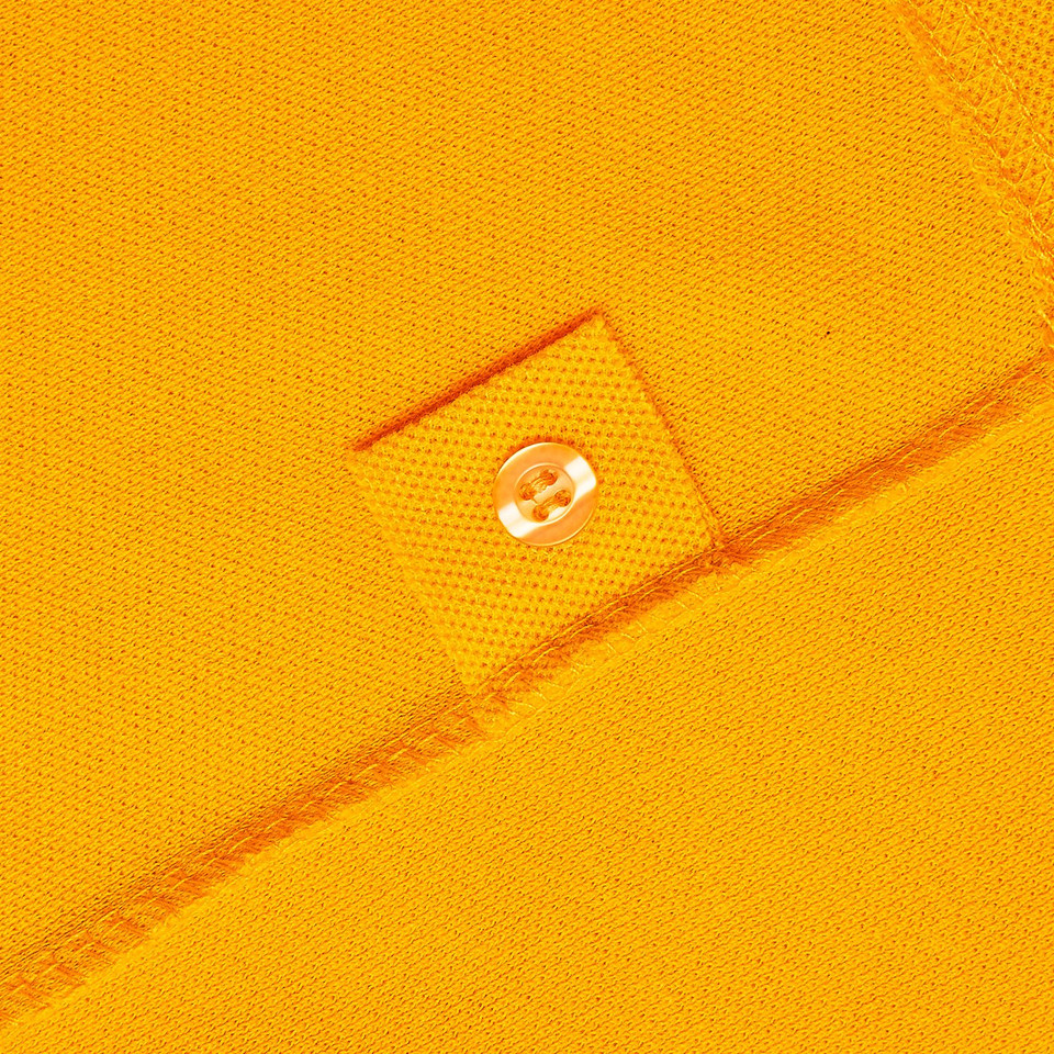Close-up of golden yellow pique polo placket with tone-on-tone button detail