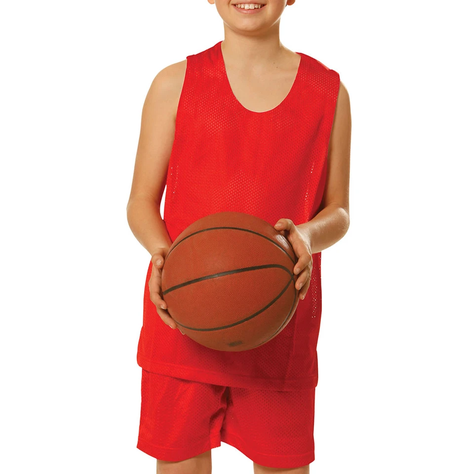 Bright red reversible basketball singlet with mesh fabric and matching shorts on young player holding basketball