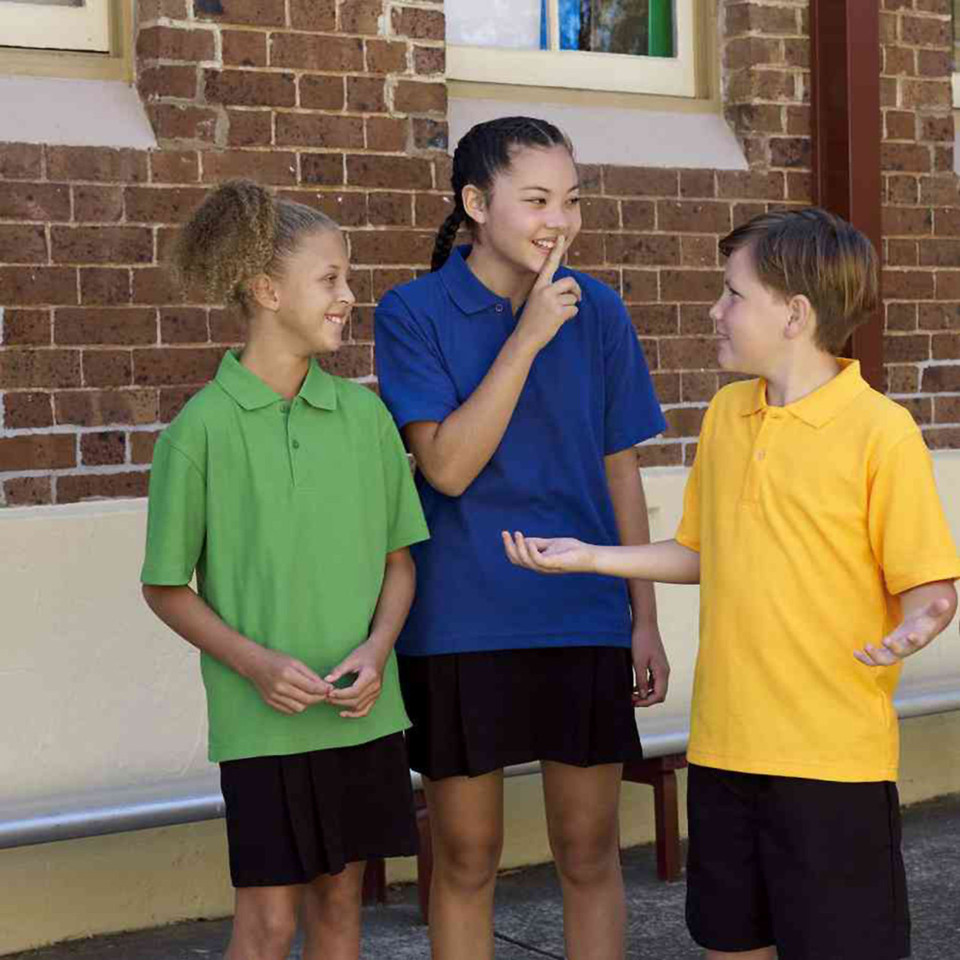 Three children wearing lime green, royal blue, and golden yellow short sleeve pique polo shirts with black collars