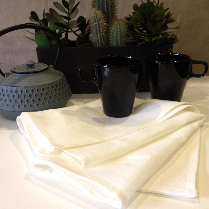 Natural white linen tea towels stacked and folded, displaying clean hemmed edges and smooth texture