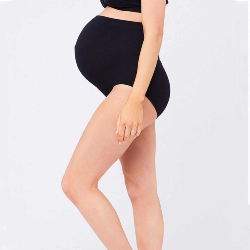 Pregnant model wearing black high-waisted seamless maternity briefs, side profile view