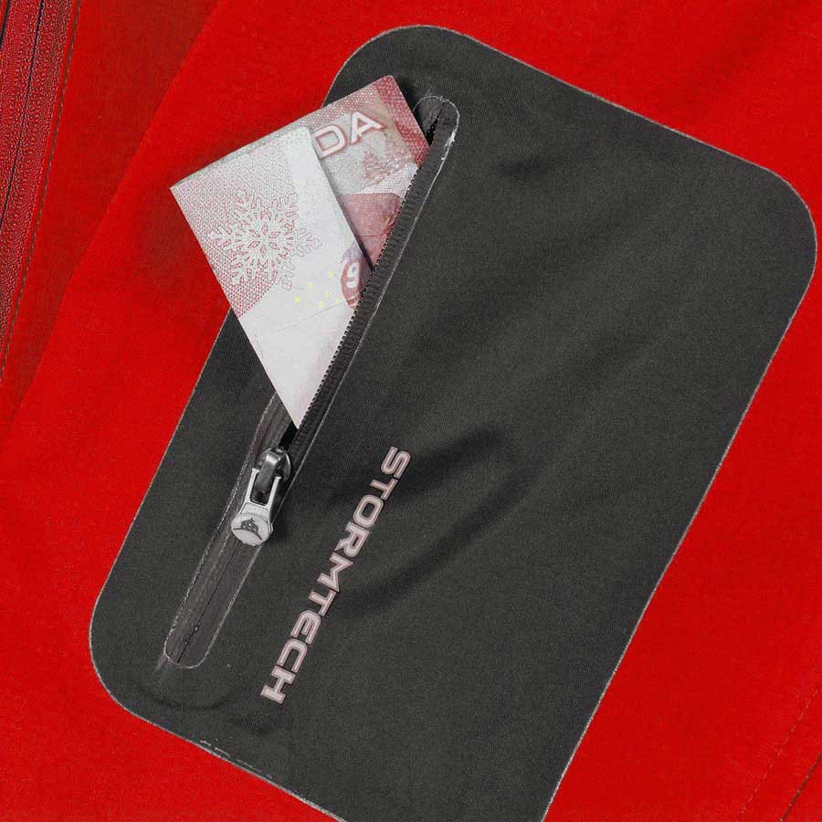 Close-up of charcoal zip security pocket on red Stormtech softshell jacket with banknote visible inside