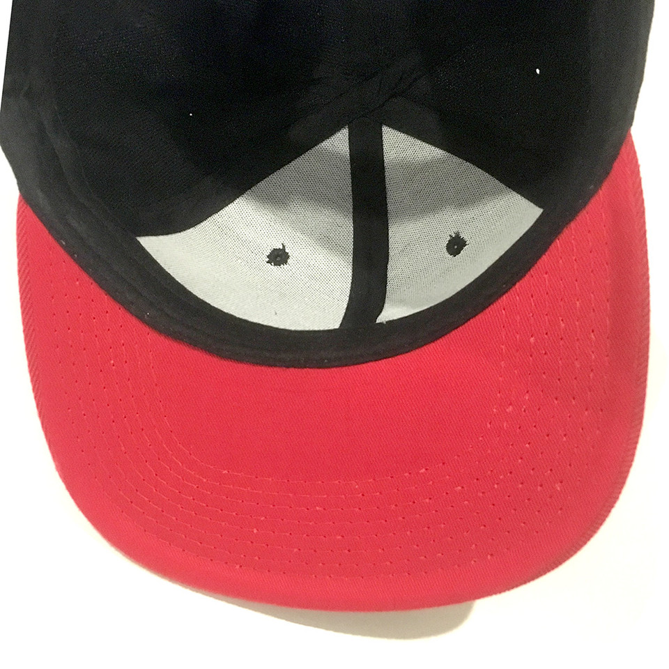 Black crown snapback cap with bright red flat peak showing white undervisor panels and adjustable closure