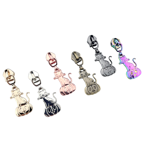 Pumpkin Kitty #5 Sewcioath zipper pulls laid down, one of each 6 colors available. Nickel,  gold, rose, antique, rainbow, and gunmetal