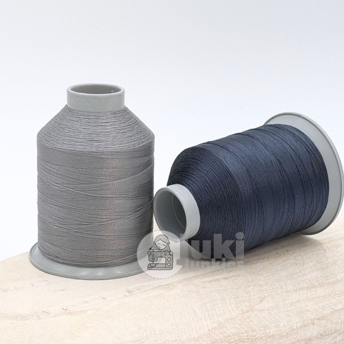 Close up of medium grey and navy colored thread spools 