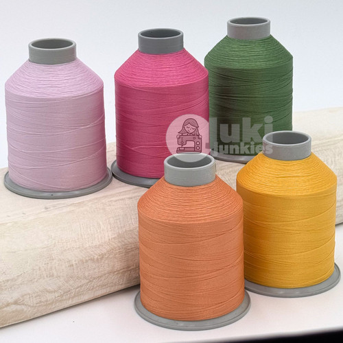Close up of light pink, pink, green, orange, and yellow thread spools