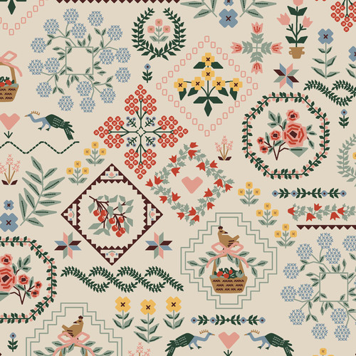 Close up of canvas linen fabric with a variety of patterns including flowers, farm animals, leaves, and hearts, on a cream colored background
