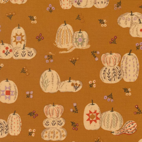 Close up of fabric with decorated pumpkins and florals on a caramel brown colored background