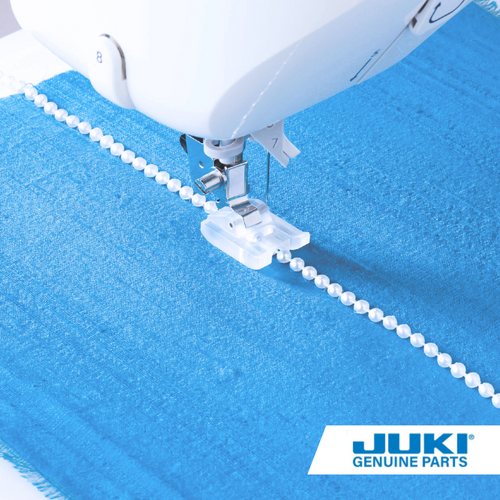 Pearl attaching presser foot sewing a strand of beads through the center groove with a zigzag stitch, smoothing attaching pearls, cording or piping to fabric