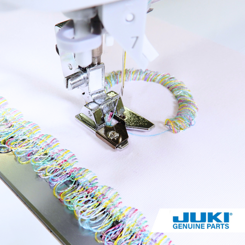 Close up of fringe presser foot for sewing machine creating loops on top of light pink fabric in variegated  rainbow thread.