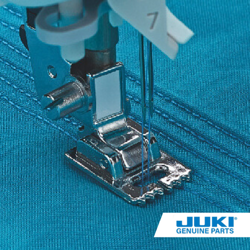 Close up of wide pintuck presser foot for sewing machine creating pintucks on a blue fabric.