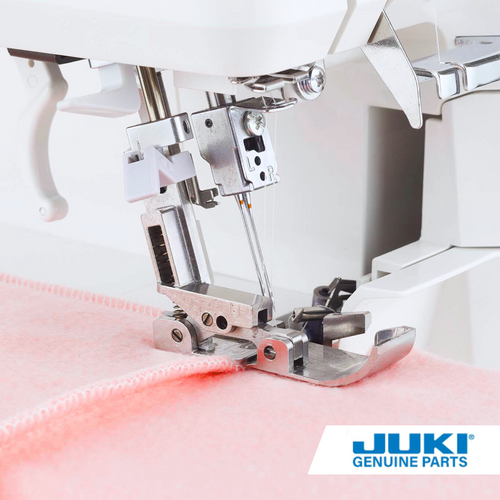 Juki tractor presser foot on a serger sewing over a seam on pink fabric, smoothly feeding multiple layers while preventing skipped stitches at thick junctions such as collars and cuffs.