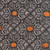 Close up of fabric with a medallion tile pattern and orange pumpkins on a black background