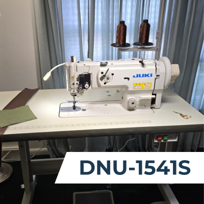 A Juki DNU-1541S industrial sewing machine with two spools of brown thread, positioned in a lift cutout of a sewing table.