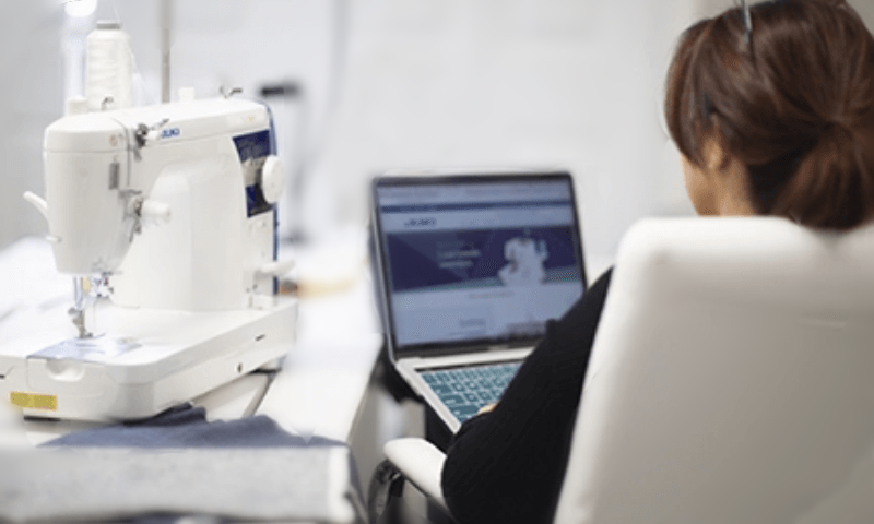 Person sitting in front of sewing machine and laptop