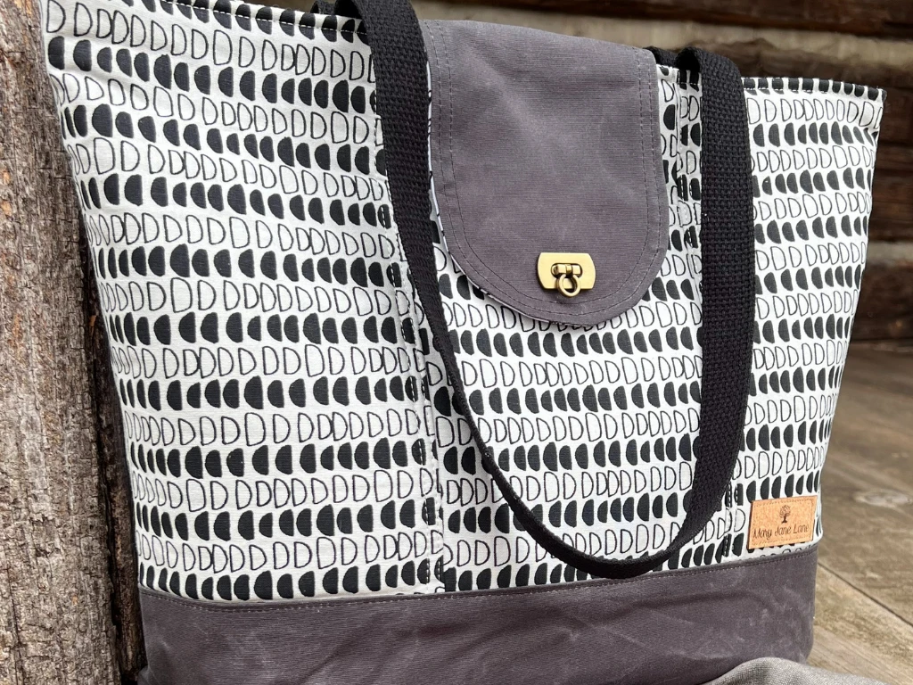 Patterned tote bag with a leather strap and gray bottom panel.