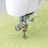 Close-up of one-fifth inch free motion quilting sewing machine presser foot quilting on yellow fabric