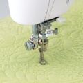 Close-up of one-fifth inch free motion quilting sewing machine presser foot quilting on yellow fabric
