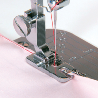 Rolled hem presser foot in use, sewing a narrow hem on pink fabric—demonstrates the hemmer's function and stitch finish
