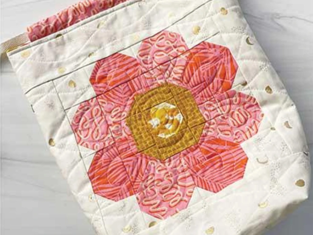 Quilted fabric pouch appliqu\u00e9d with a pink and gold flower.