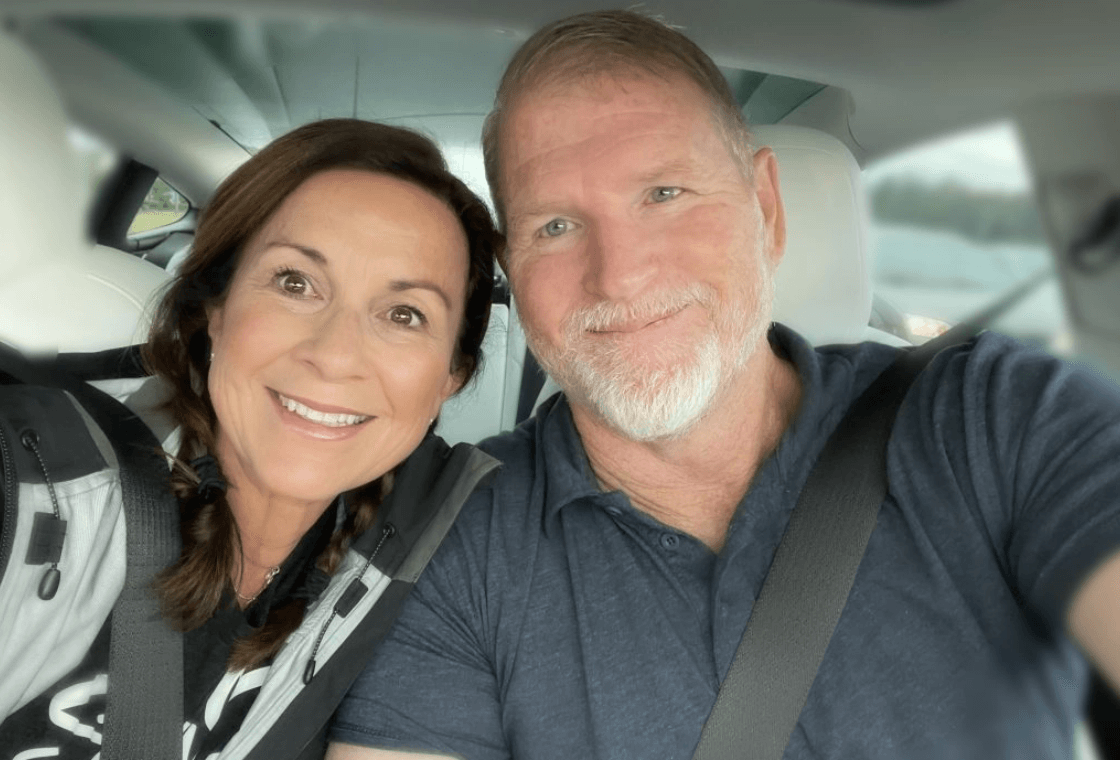 Janome Junkies creators and owners, Gigi and David Wilson, smiling and taking a selfie together inside a car.